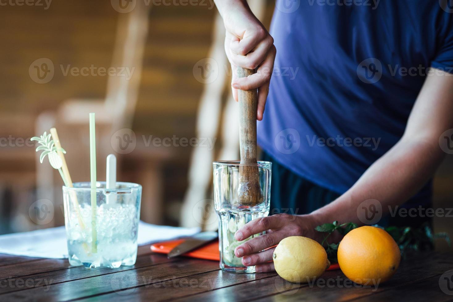 bartendern förbereder fruktalkoholcocktail baserad på lime, mynta, apelsin, läsk foto