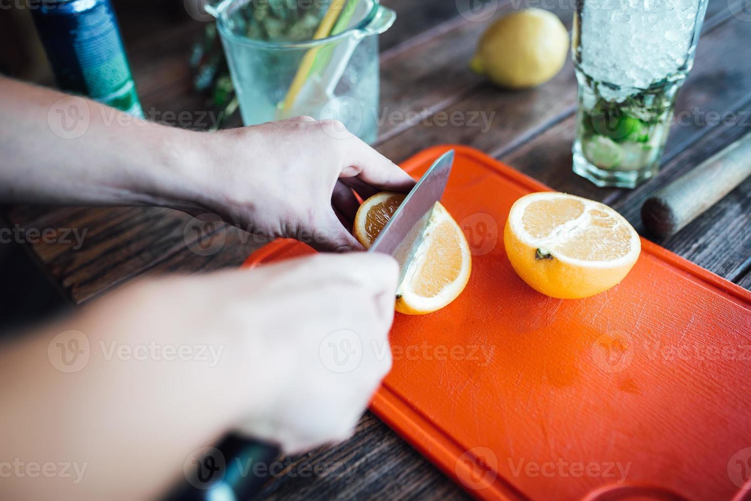 bartendern förbereder fruktalkoholcocktail baserad på lime, mynta, apelsin, läsk foto