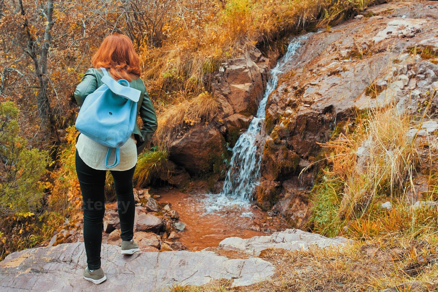 en kvinna beundrar ett litet vattenfall i skogen. foto