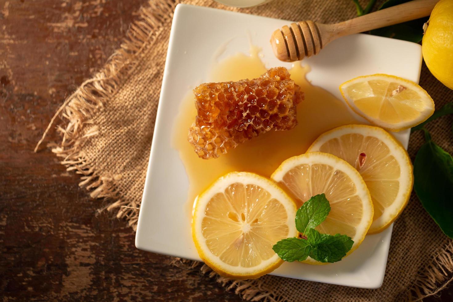 citronsaft med honung på träbord, citroner och salvia löv foto