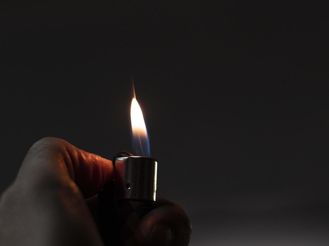 mens händer håller tändare, eld från cigarett foto