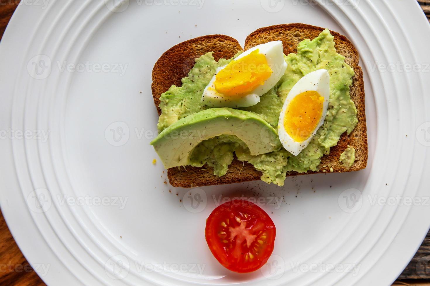 rostat bröd med avokado och ägg på tallriken foto