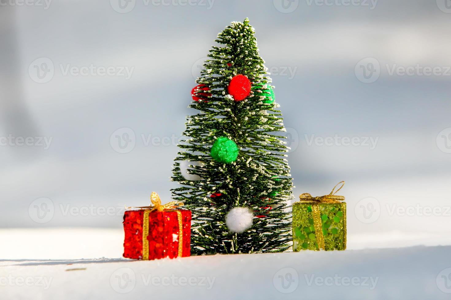 julgran på snö med röd och grön presentask foto