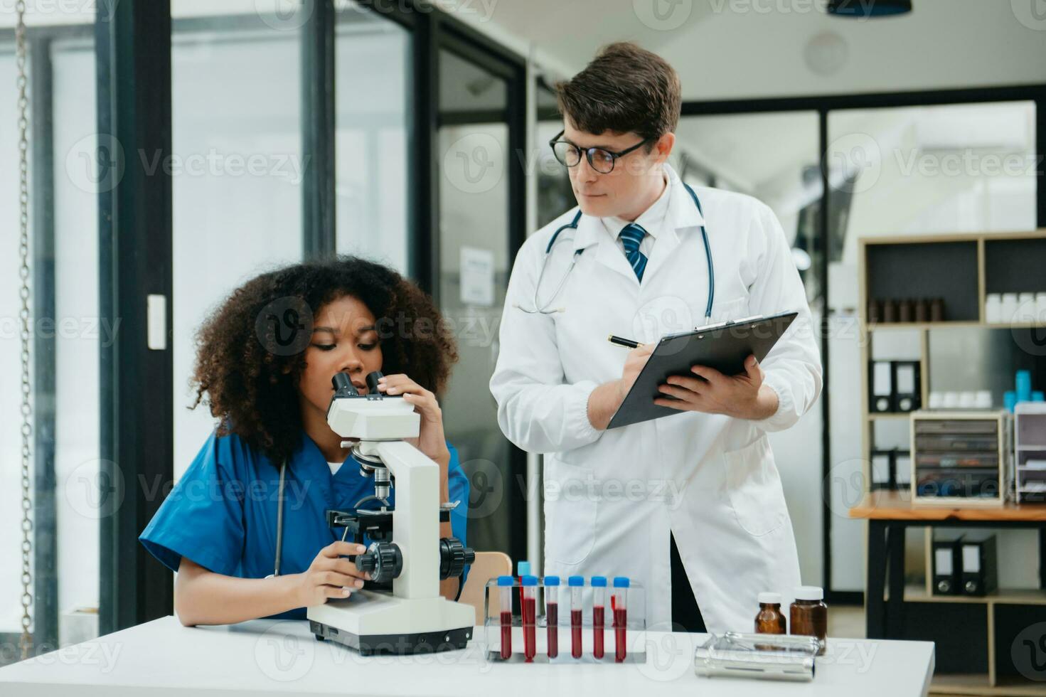 två forskare eller medicinsk tekniker arbetssätt, har en medicinsk diskutera möte med ett asiatisk senior kvinna forskare handledare i de laboratorium med uppkopplad läsning, testa prover foto