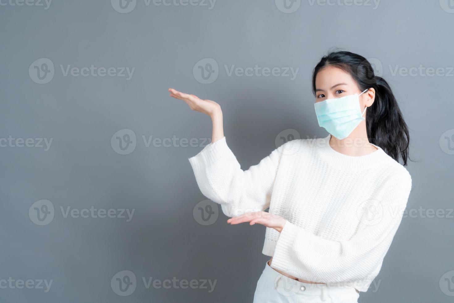 asiatisk kvinna som bär medicinsk ansiktsmask skyddar filterdamm pm2.5 anti-förorening, anti-smog och covid-19 med handpresenterande foto