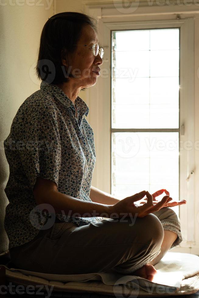 senior asiatisk buddhistkvinna som övar meditation för ett fridfullt sinnes- och hälsoliv. mindfulness och religion koncept foto