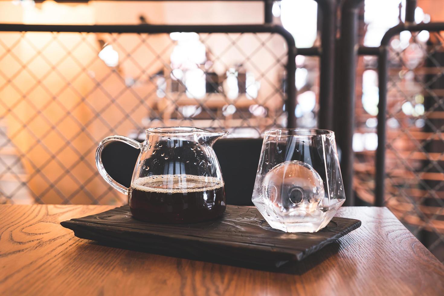 kall dropp svart kaffekanna med glas och is i kafé och restaurang foto