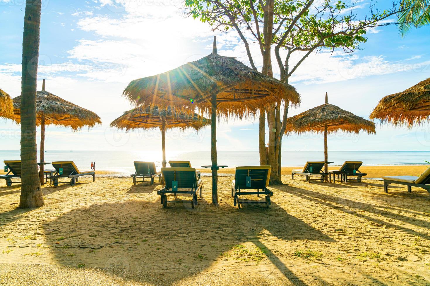 paraplyer och solstolar med kokospalmer och havsstrandbakgrund och blå himmel - semester- och semesterbegrepp foto