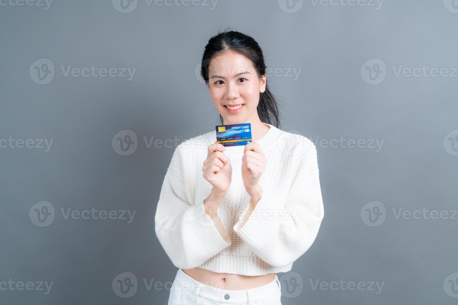 stående av en härlig ung asiatisk kvinna i tröja som visar kreditkort med kopieringsutrymme foto