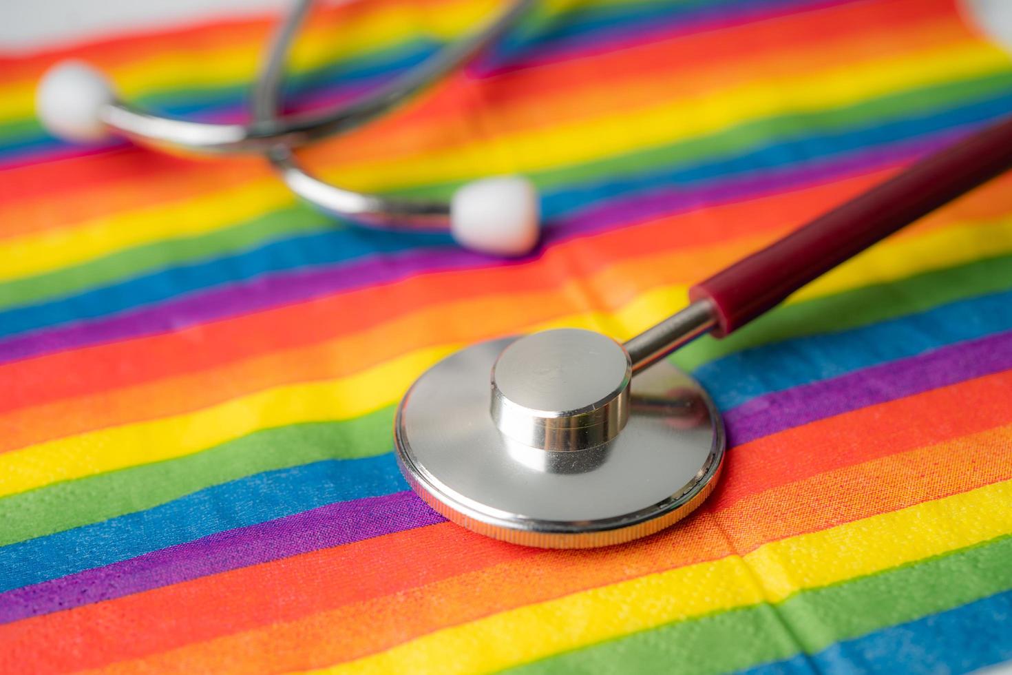 svart stetoskop på regnbågsflaggabakgrund, symbol för HBT stolthet månad firar årliga i juni sociala, symbol för homosexuella, lesbiska, bisexuella, transpersoner, mänskliga rättigheter och fred. foto
