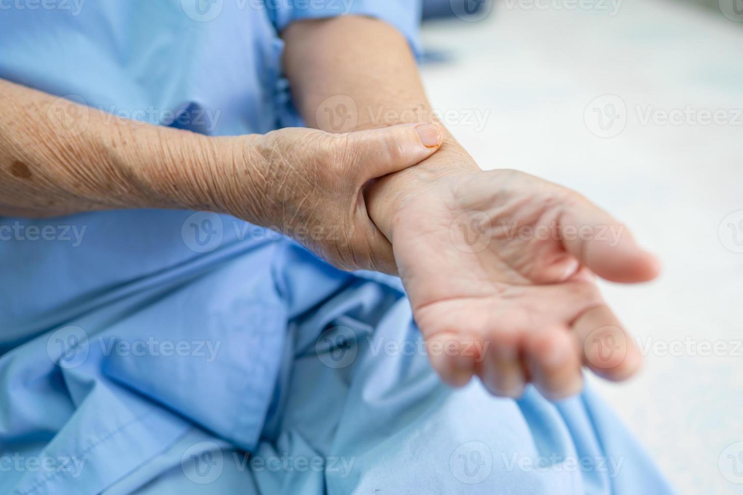 asiatisk senior eller äldre gammal damkvinnapatient känner smärta hennes hand på sängen i vårdavdelningen, hälsosamt starkt medicinskt koncept. foto