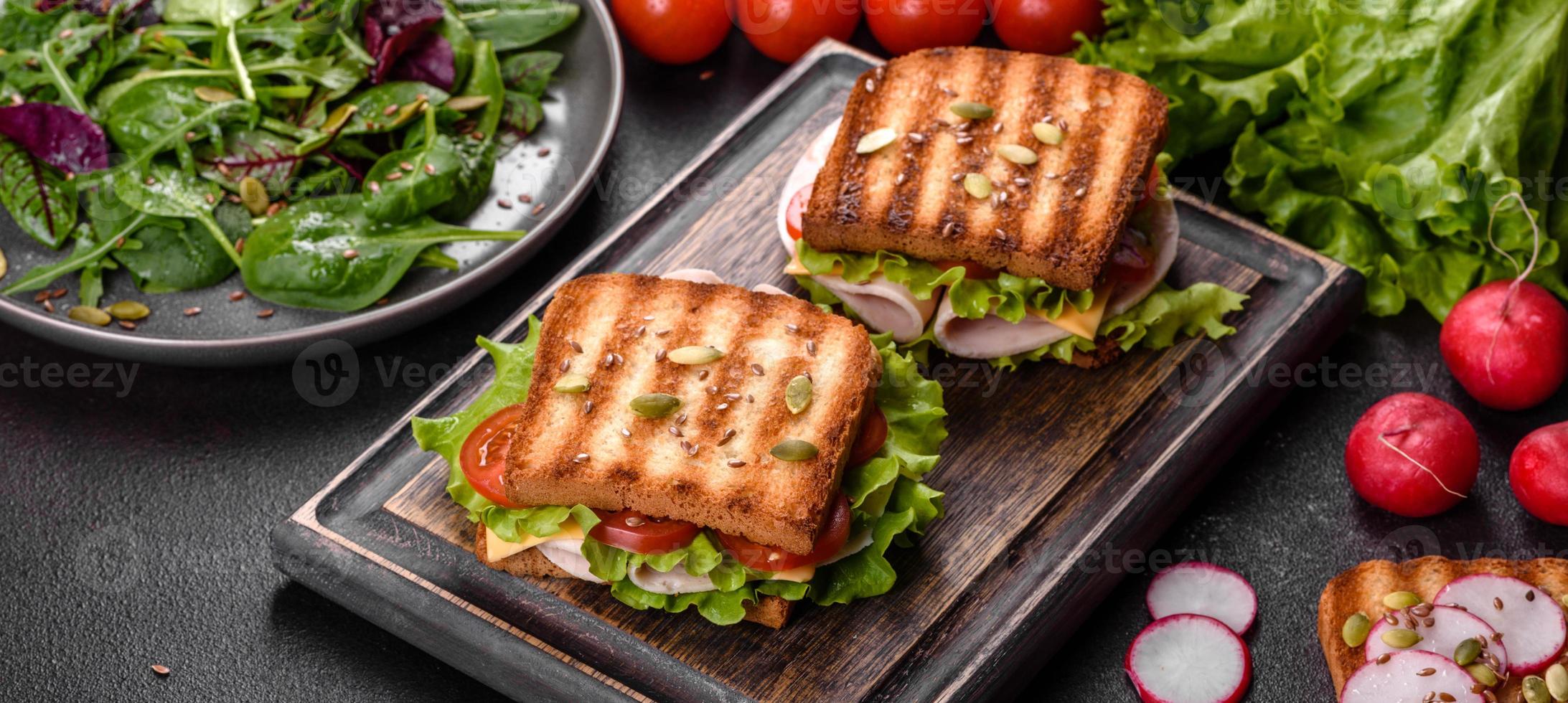 utsökt smörgås med skarp toast, skinka, sallad och tomater foto