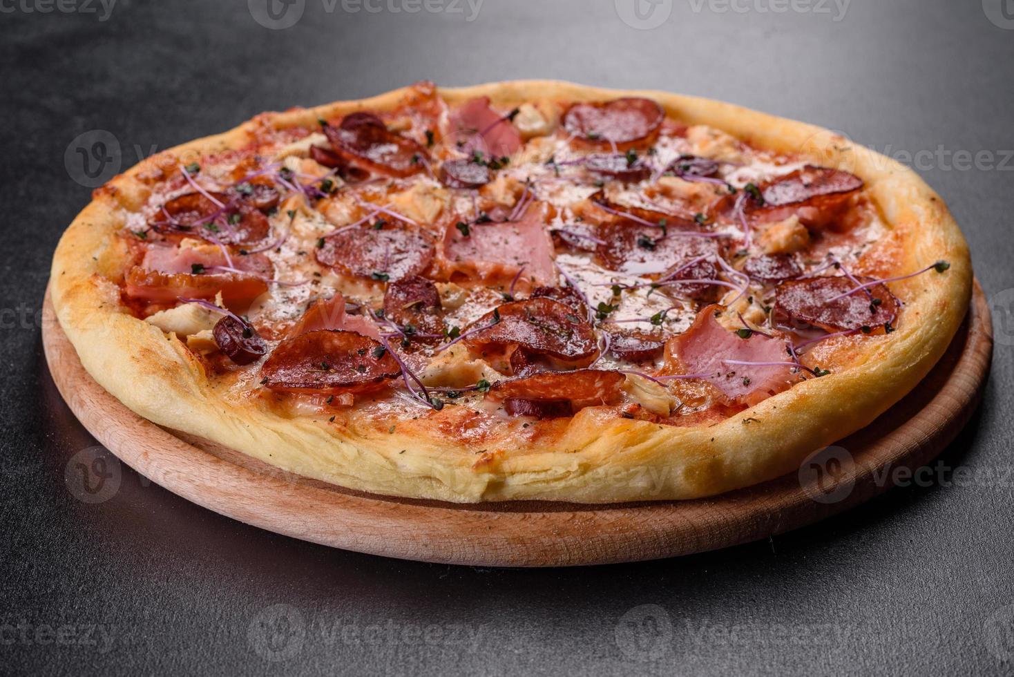 läcker färsk ugnspizza med tomater, salami och bacon på en mörk betongbakgrund foto