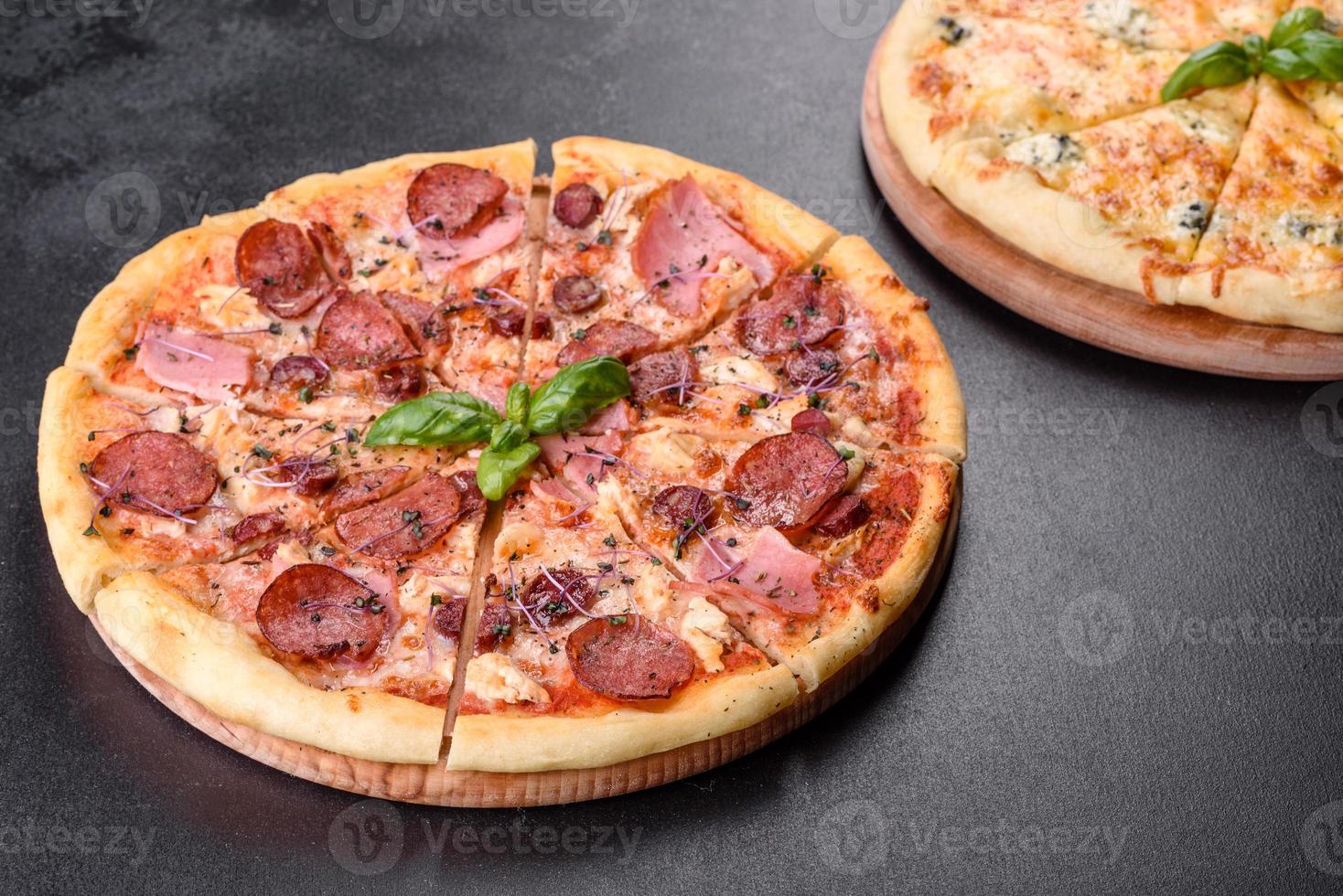 läcker färsk ugnspizza med tomater, salami och bacon på en mörk betongbakgrund foto