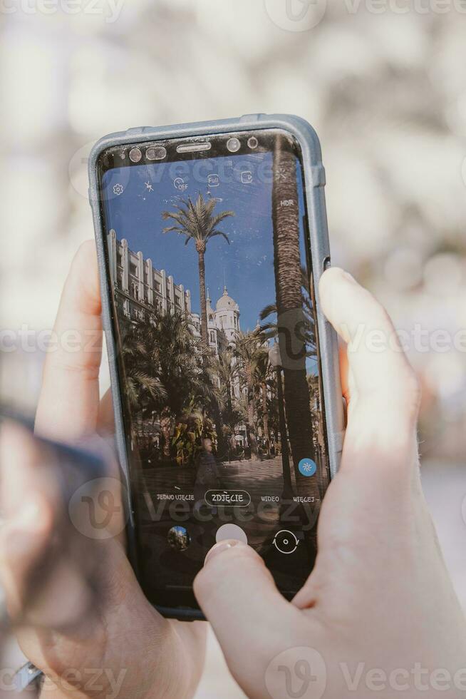 mobil telefon i händer medan tar Foto explanada i Alicante, Spanien