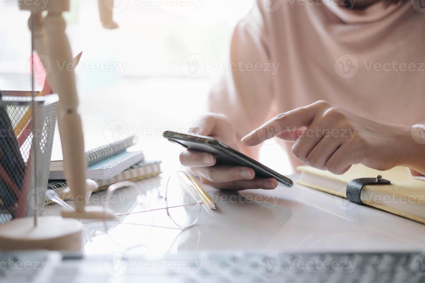 kvinna som håller smartphonen och använder bärbar dator hemma foto