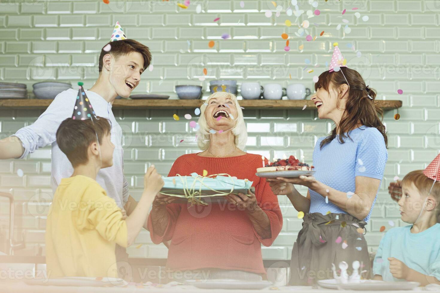 mor och söner fira mormors bithday i deras kök foto