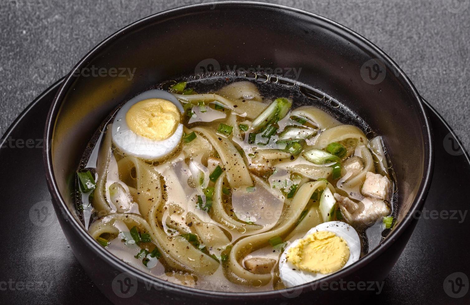 färsk läcker varm soppa med nudlar och vaktelägg i en svart tallrik foto