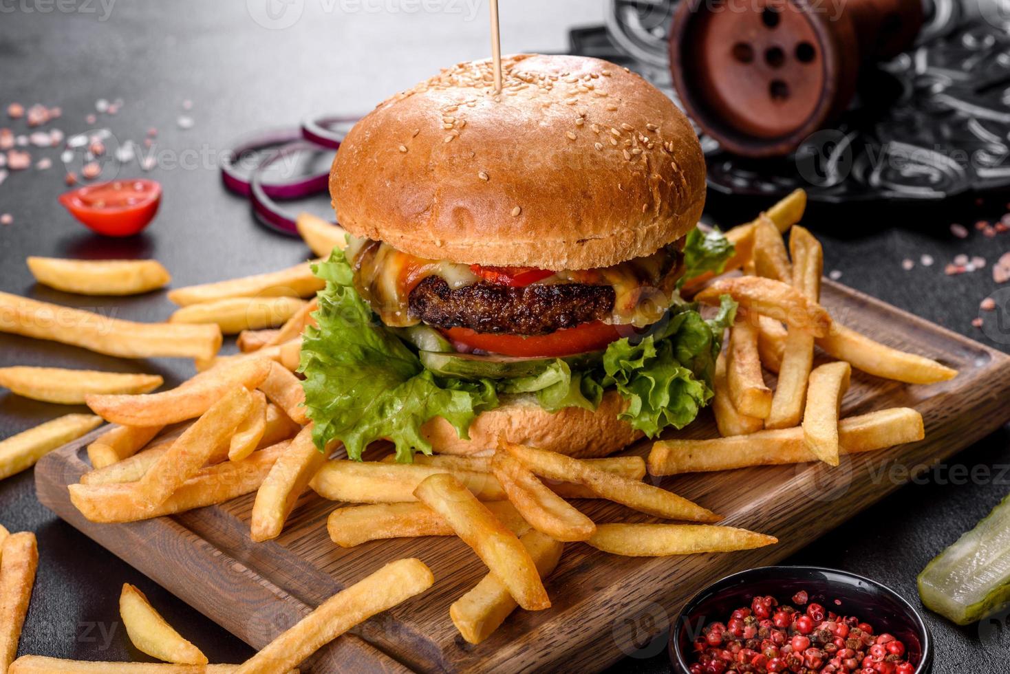 läcker färsk burger med nötköttkotlett, tomater och sallad med pommes frites foto