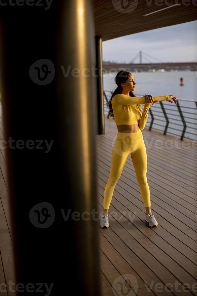 ung kvinna som sträcker sig på flodstranden foto