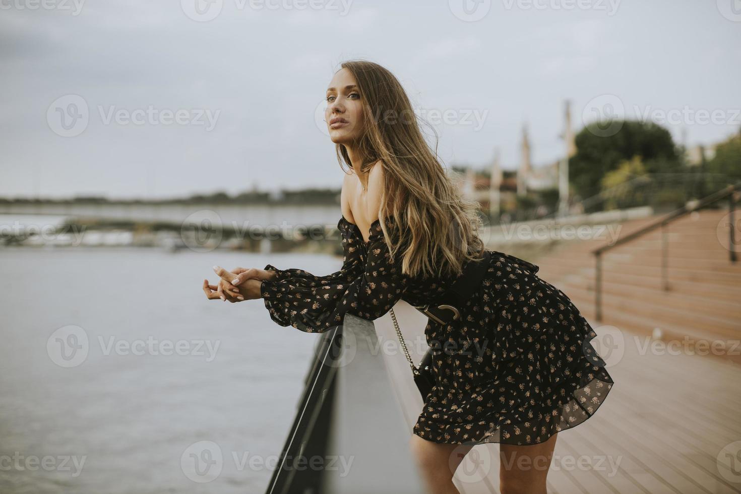 ung brunettkvinna för långt hår som står på flodstranden foto