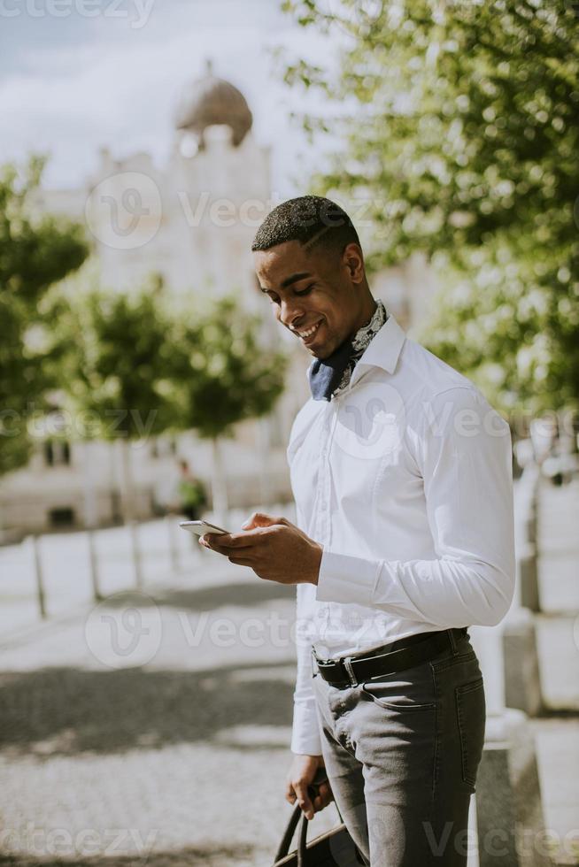 ung afrikansk amerikanaffärsman som använder en mobiltelefon foto