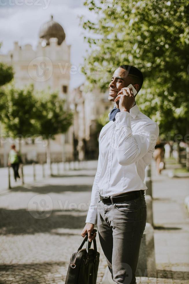 ung afrikansk amerikanaffärsman som använder en mobiltelefon foto