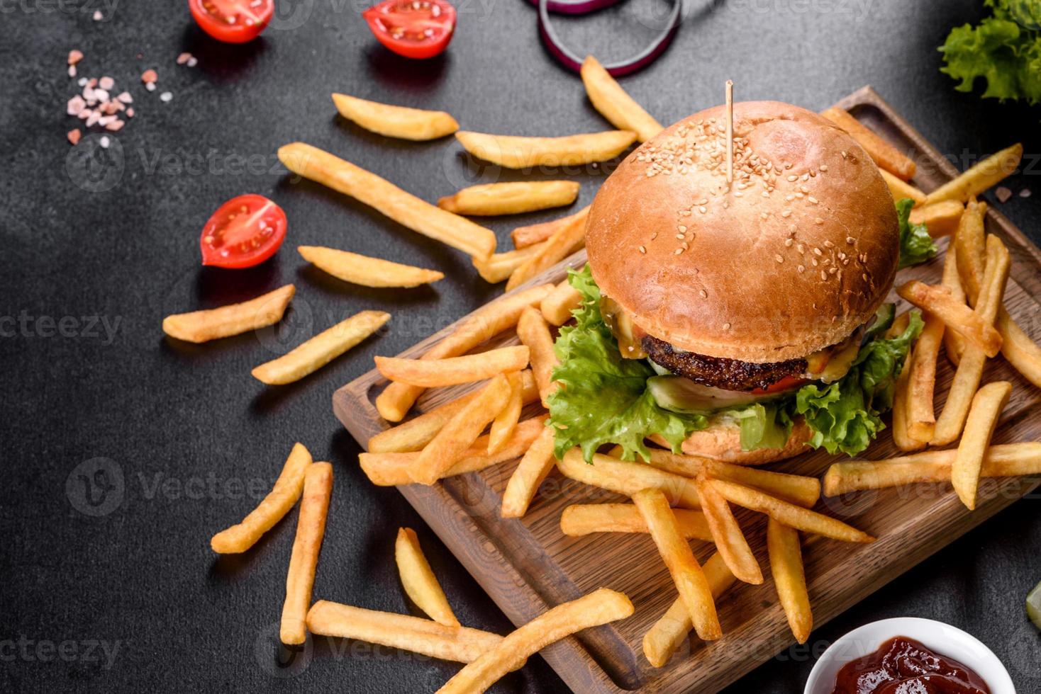 läcker färsk burger med nötköttkotlett, tomater och sallad med pommes frites foto