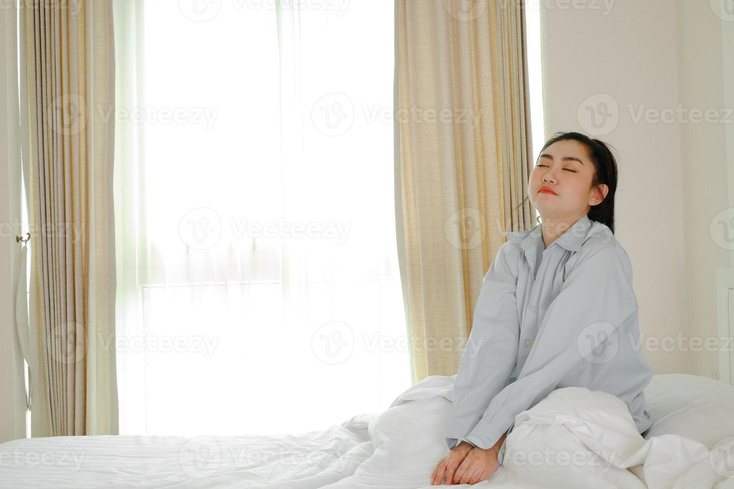 asiatiska kvinnor vaknar på en säng i sovrummet foto