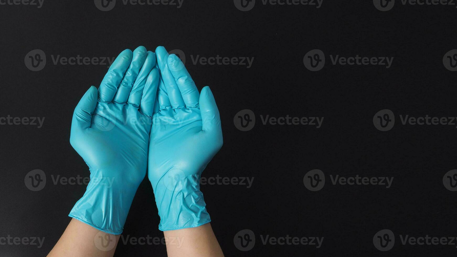 två hand med handskar håller på med tecken för tigga eller hjälp på svart bakgrund. foto