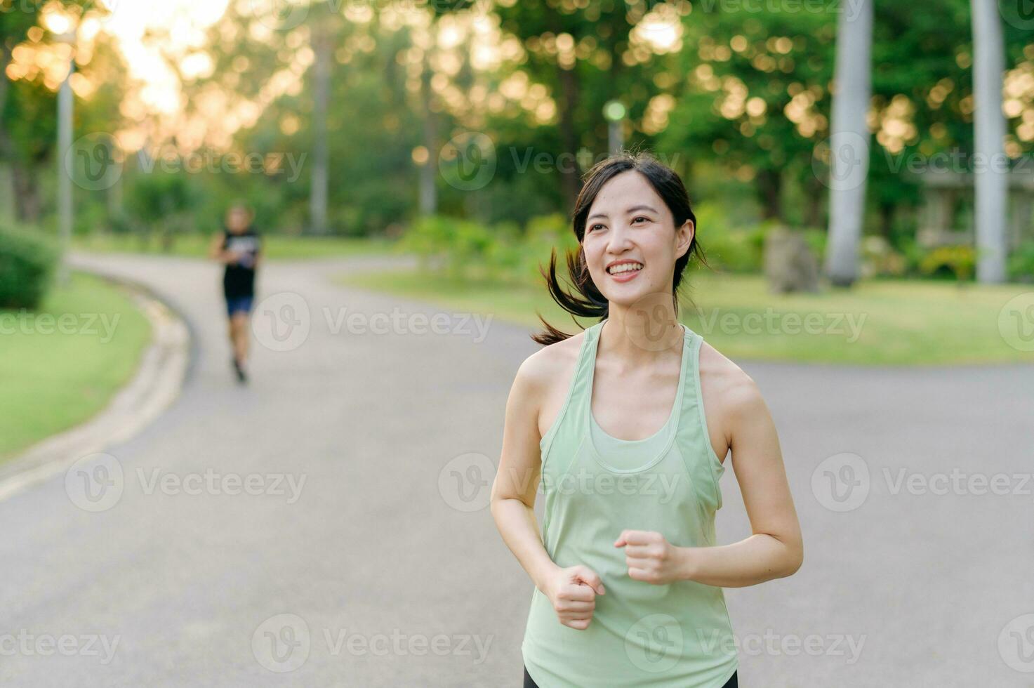 passa asiatisk ung kvinna joggning i parkera leende Lycklig löpning och njuter en friska utomhus- livsstil. kvinna joggare. kondition löpare flicka i offentlig parkera. friska livsstil och wellness varelse begrepp foto