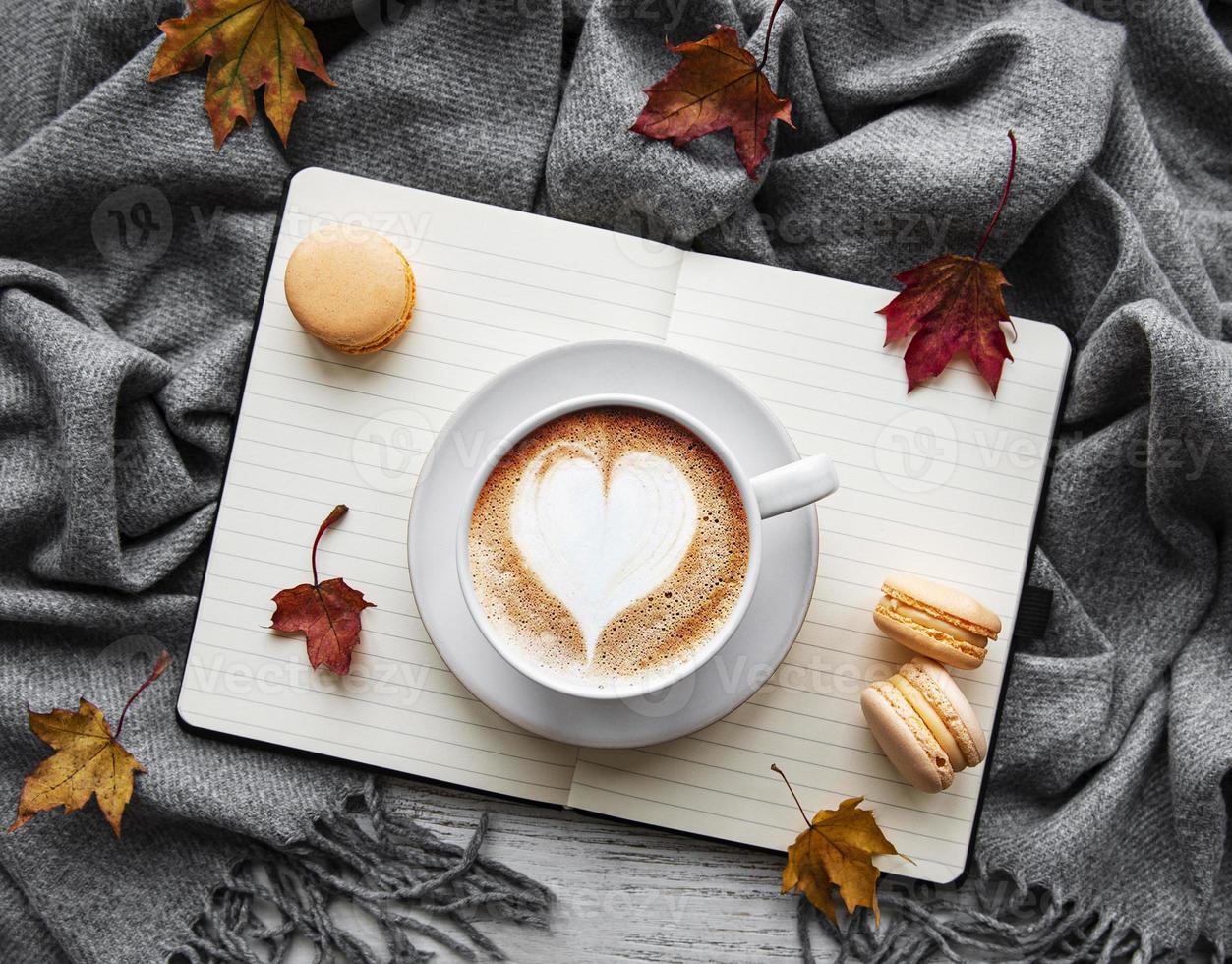 lönnlöv, anteckningsbok, kaffekopp och halsduk. foto