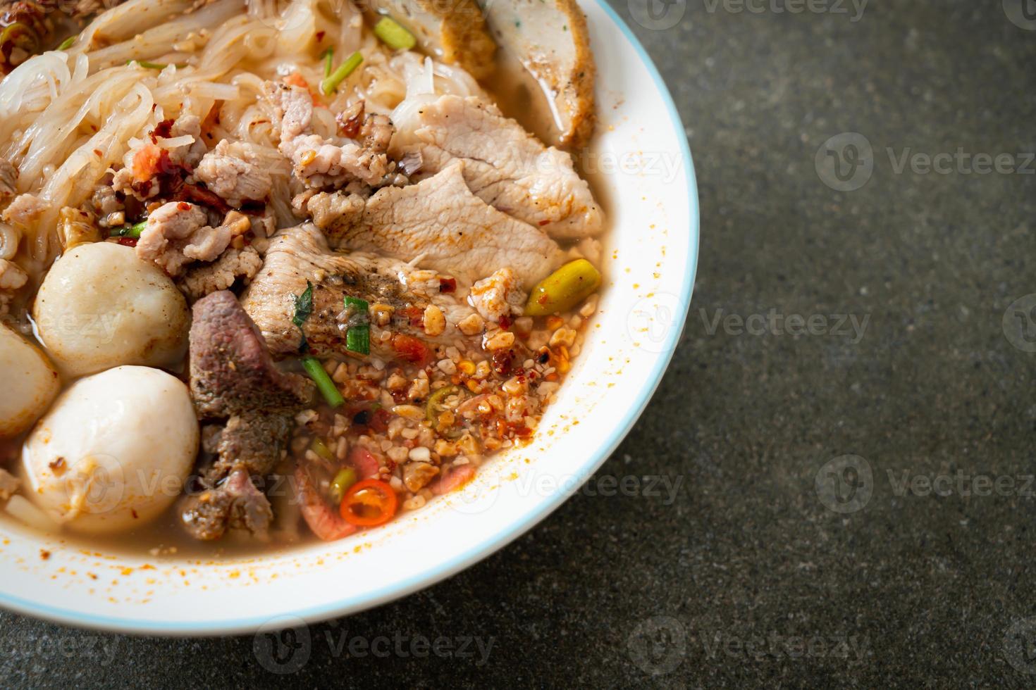 nudlar med fläsk och köttbullar i kryddig soppa eller tom yum nudlar i asiatisk stil foto