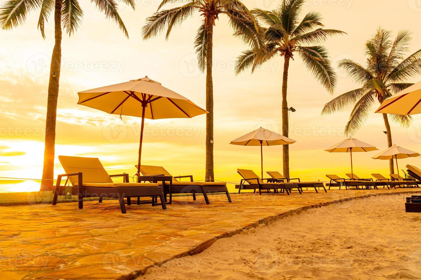 paraply och stol runt poolen i hotellresorten med soluppgång på morgonen foto