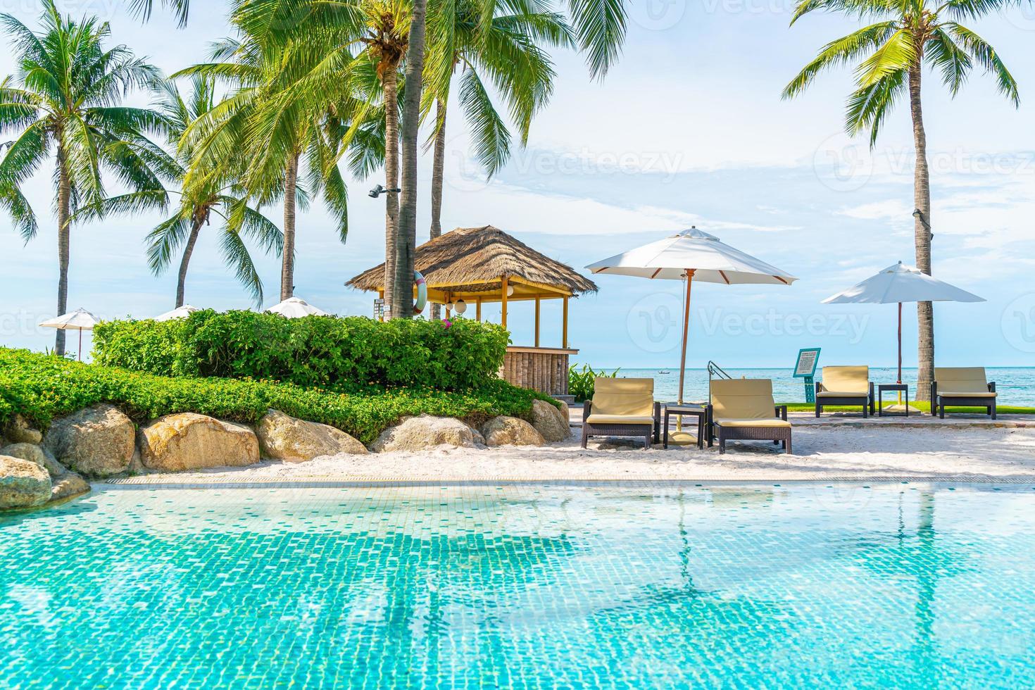 vacker tropisk strand och hav med paraply och stol runt poolen i hotellresorten foto