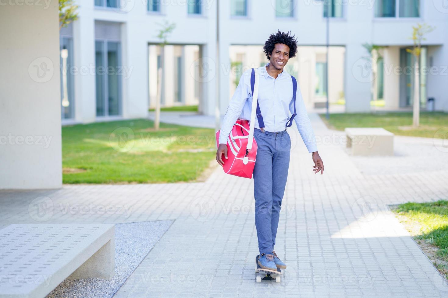 svart affärsman ridning skateboard nära kontorsbyggnad. foto