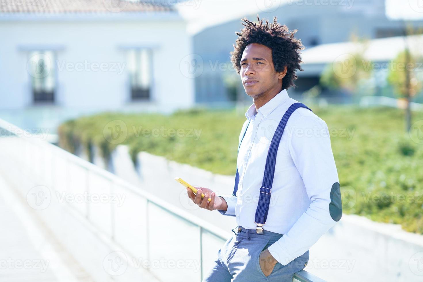 svart man med afro frisyr med en smartphone foto