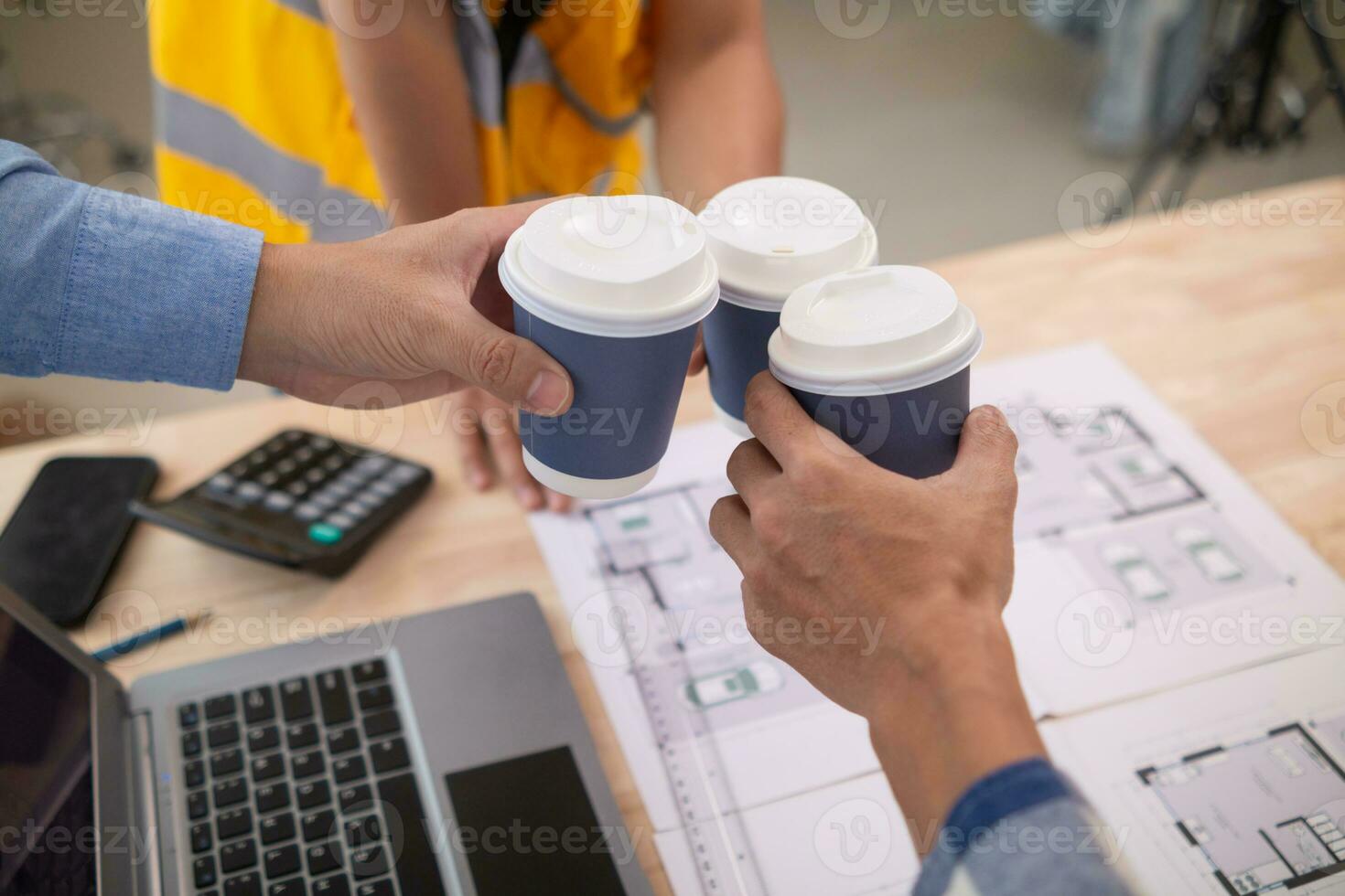 lag ingenjörer, arkitekter och verklig egendom investerare karnade över kopp av varm kaffe till gratulera dem deras framgångsrik projekt design inom budget. varm kaffe krock begrepp till fira i kontor foto