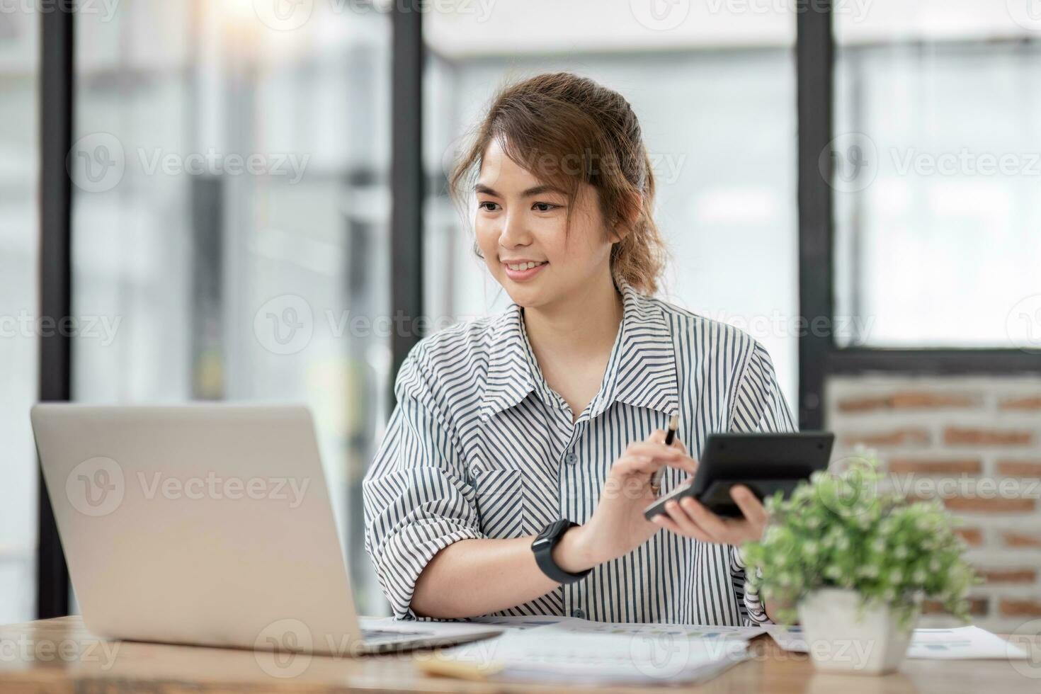 asiatisk företag kvinna använder sig av en kalkylator beräknande finansiell bekostnad på kontor, Tryck kalkylator knapp finansiera analyserar foto