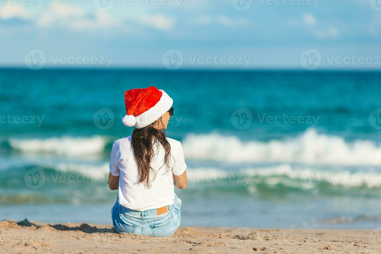 ung kvinna i santa hatt på jul strand högtider foto