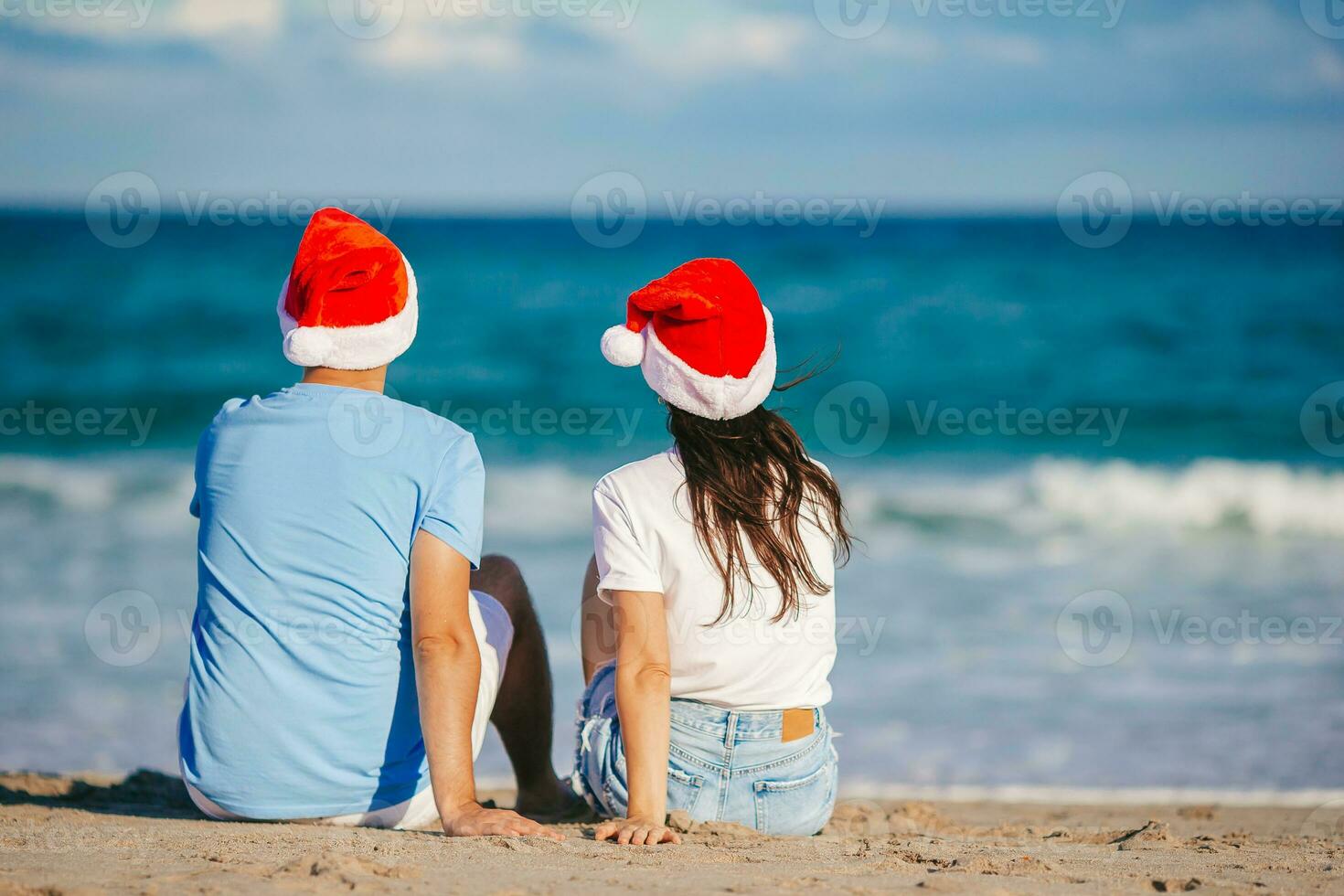 jul Lycklig par i santa hattar på strand semester foto