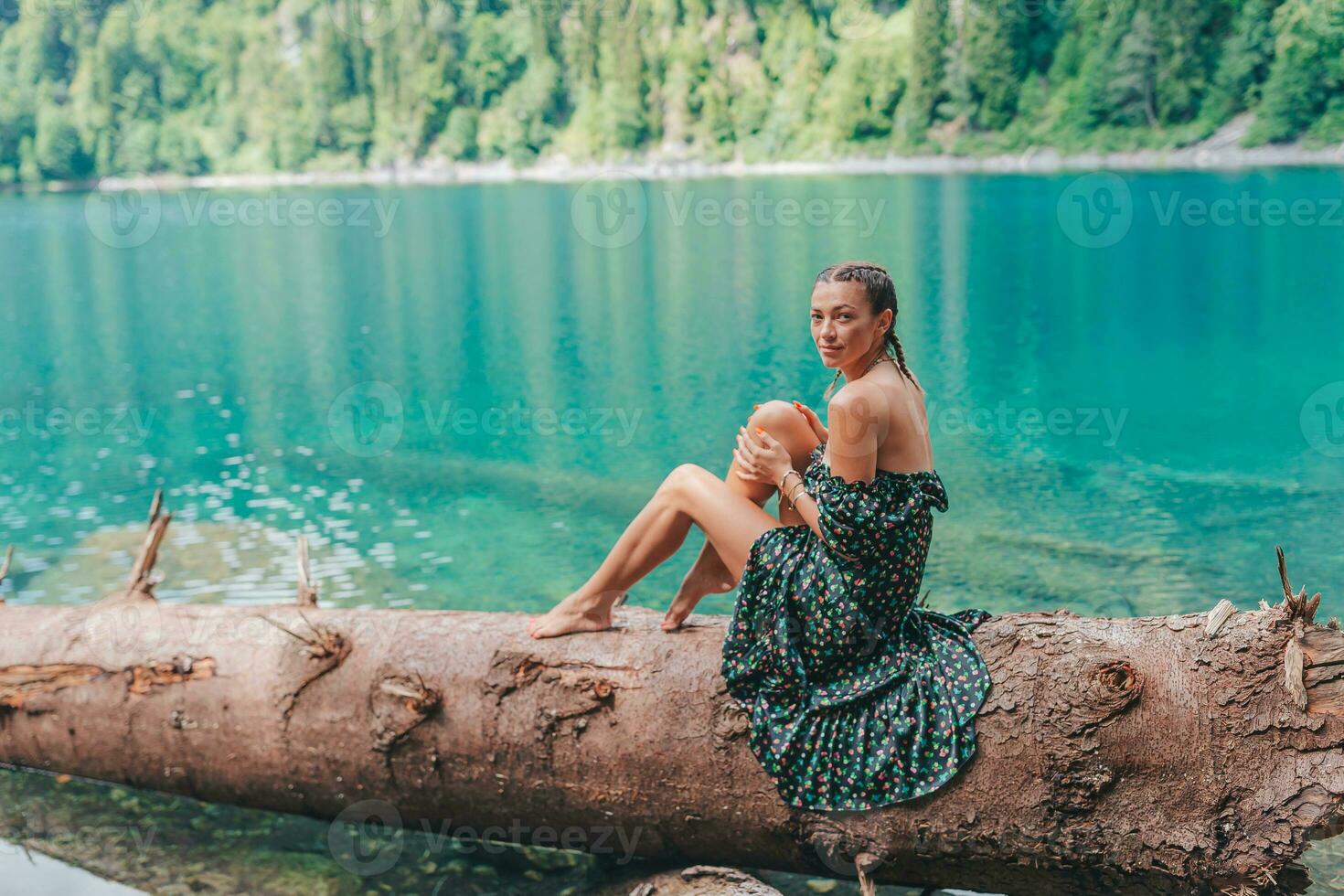 Lycklig romantisk kvinna Sammanträde förbi sjö stänk vatten på perfekt blå sjö ritsa. abkhazia foto