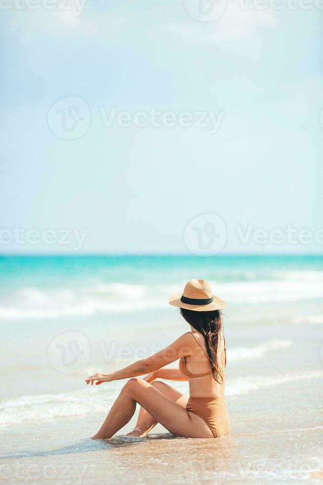 ung Lycklig kvinna på de strand njut av henne sommar semester. kvinna koppla av på de havsstrand foto