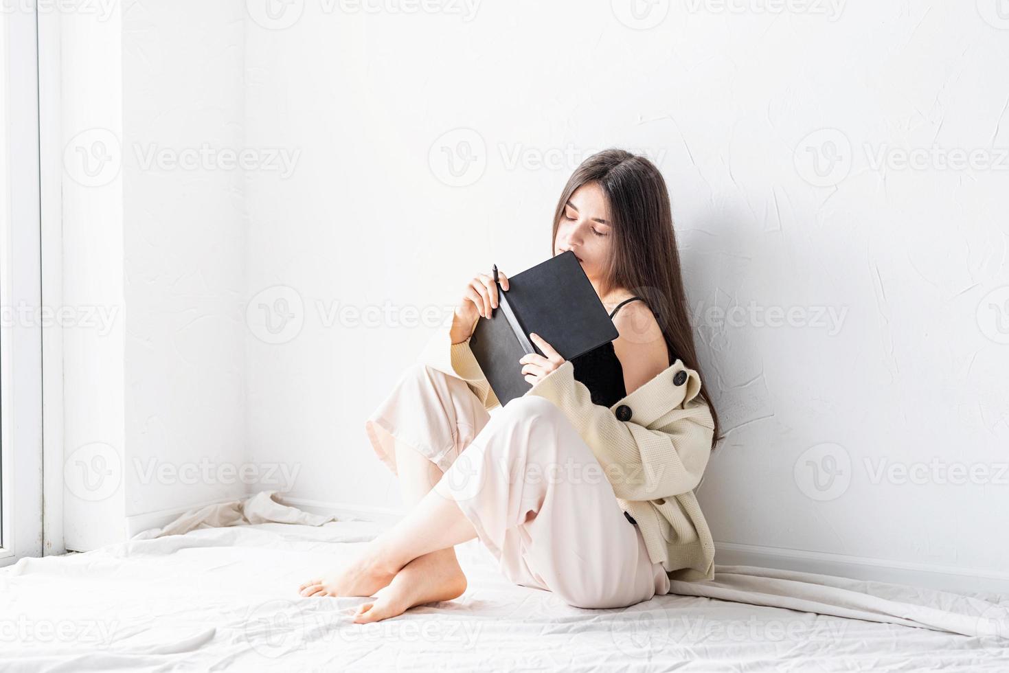 kvinna skriver anteckningar sitter på golvet drömmer foto