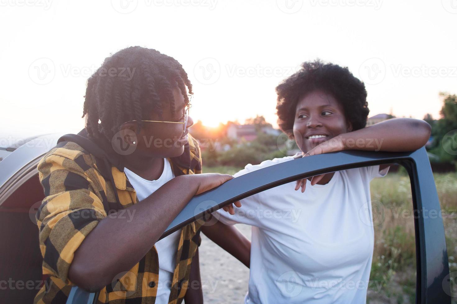 två glada afroamerikanska kvinnor nära bilen vid solnedgången, livsstil foto