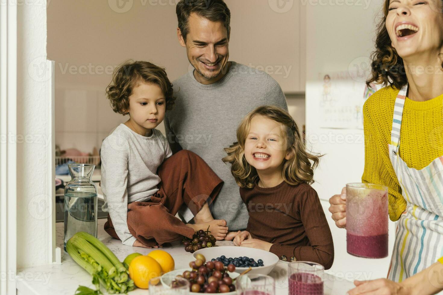 Lycklig familj framställning en smoothie i kök foto