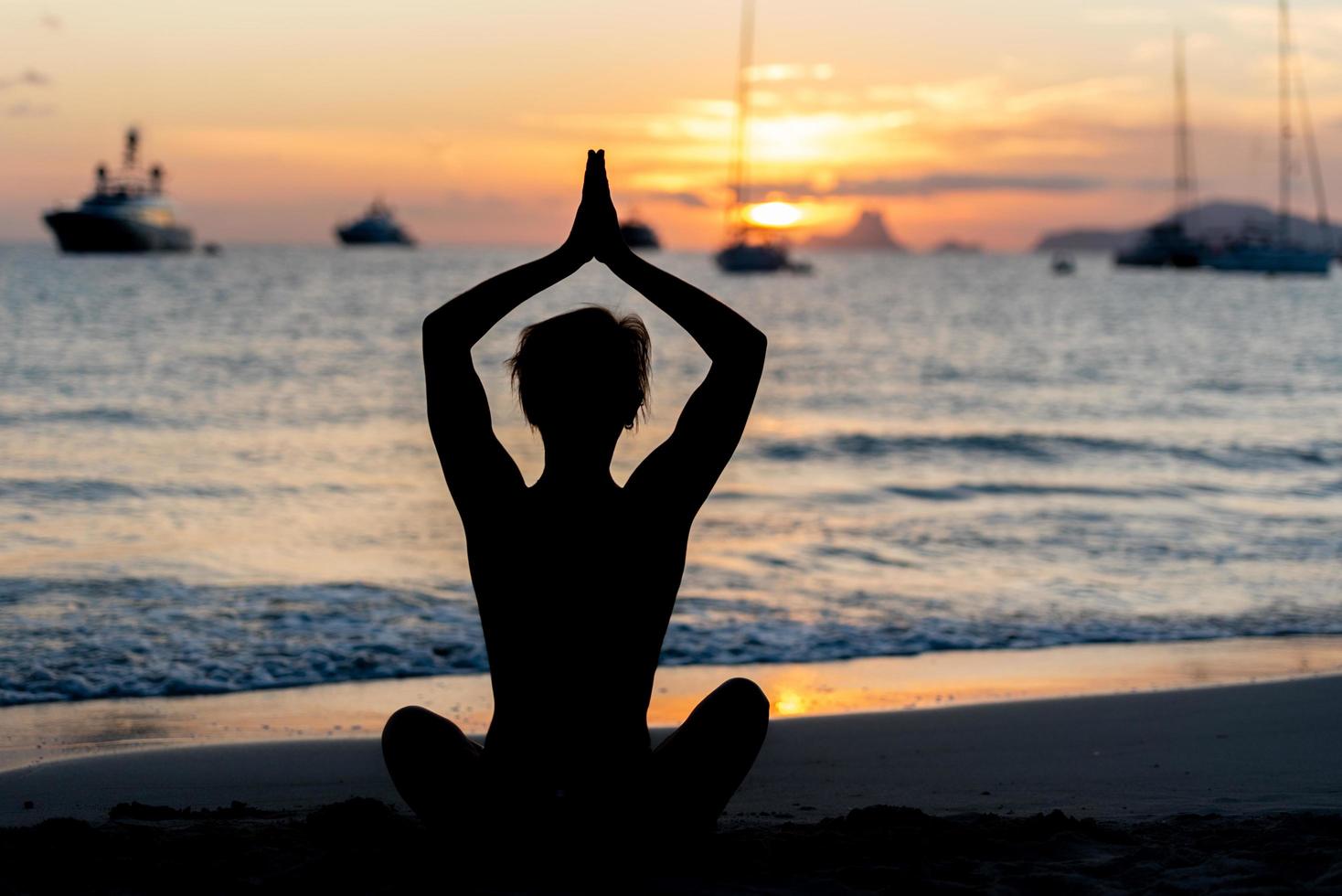 silhuett av fitnessmodell som gör yoga vid solnedgången foto