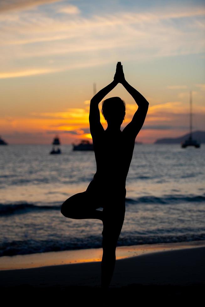 silhuett av fitnessmodell som gör yoga vid solnedgången foto