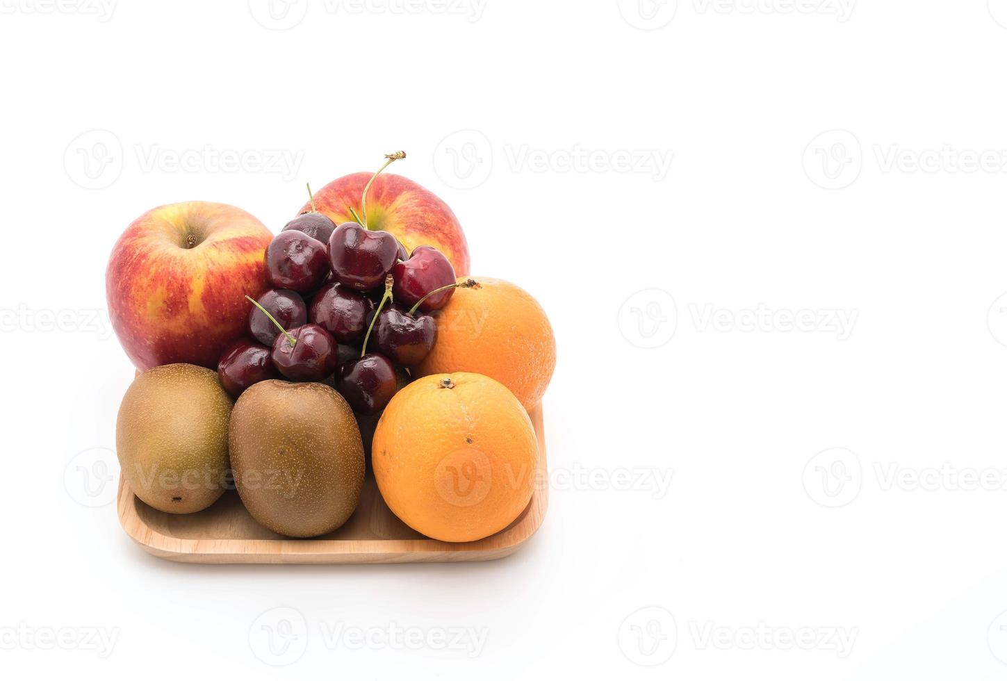 blandad frukt i träplatta på vit bakgrund foto