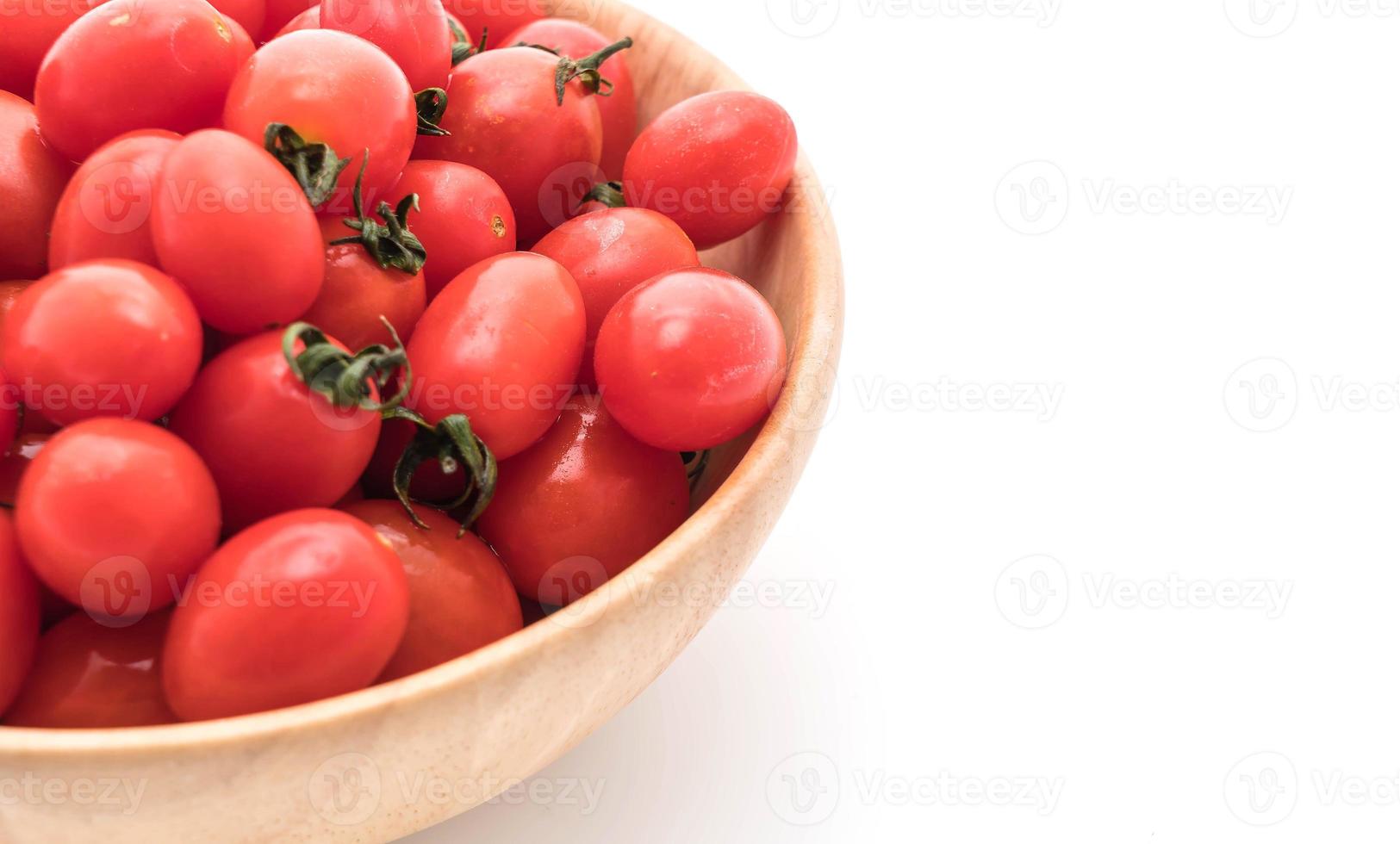 färska tomater i träskål på vit bakgrund foto